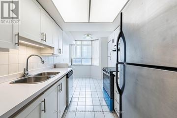 Brampton (Fletcher's Creek South) condo for rent - A modern kitchen with white cabinets and a stainless steel refrigerator.