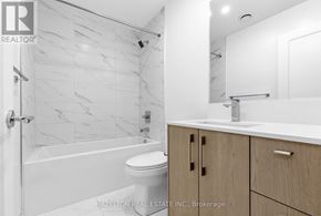 Toronto (Yonge-Eglinton) condo for rent - A white bathroom with a marble tile wall and a wooden cabinet.