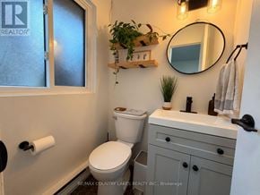 Ramara townhouse for rent - A bathroom with a toilet, sink, mirror, and a plant.