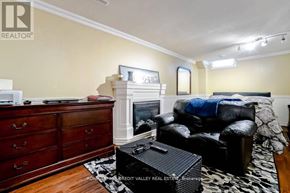 Brampton (Fletcher's West) apartment for rent - A living room with a black leather couch, a fireplace, and a wooden dresser.