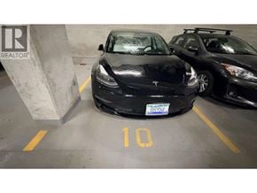 Vancouver apartment for rent - A black Tesla car is parked in a parking spot with the number 10 on the ground.