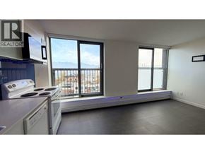 Vancouver apartment for rent - A kitchen with a stove top oven and a window overlooking a balcony.