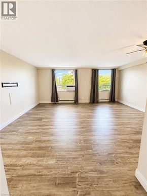 Kitchener condo for rent - A spacious room with wooden flooring and a ceiling fan.
