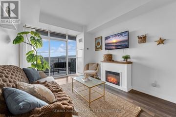 Grimsby (Grimsby Beach) condo for rent - A living room with a sofa, a fireplace, and a television on the wall.