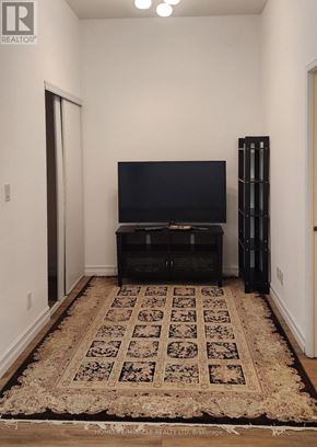 Toronto (Willowdale East) condo for rent - A black entertainment center with a flat screen TV sits in a room with a patterned rug.