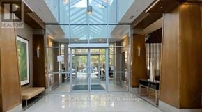Toronto (Willowdale East) condo for rent - The lobby of a building with a glass ceiling and a sign that reads "HOMELIFE/MIRACLE REALTY LTD, Brokerage".
