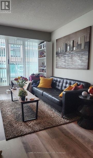 Toronto (Willowdale East) condo for rent - A black leather couch with a yellow pillow is in the center of a living room.