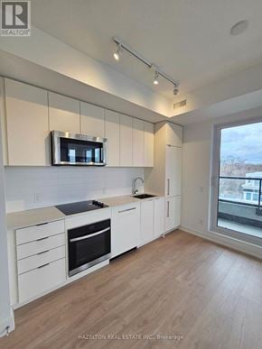 Toronto (Willowdale East) condo for rent - A modern kitchen with white cabinets and a microwave above the stove.