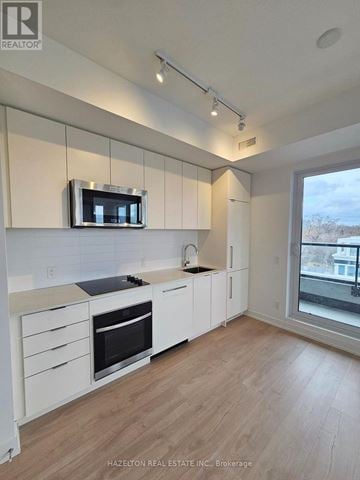 Toronto (Willowdale East) condo for rent - A modern kitchen with white cabinets and a microwave above the stove.
