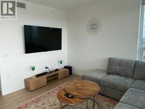 Burnaby apartment for rent - A living room with a grey couch, a wooden coffee table, and a flat screen TV mounted on the wall.