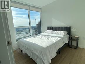 Burnaby apartment for rent - A bedroom with a large bed and a view of a construction site outside the window.