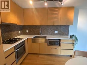 Vancouver apartment for rent - A kitchen with wooden cabinets and a granite backsplash.