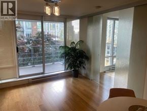 Vancouver apartment for rent - A room with a wooden floor and a large window with a view of trees and a fence outside.