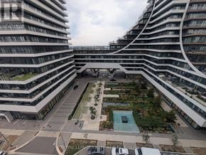 Toronto (Mimico) condo for rent - A view of a courtyard with a pool and a fountain in the middle surrounded by buildings.