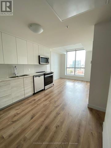 Kitchener condo for rent - A kitchen with white cabinets and a wooden floor.