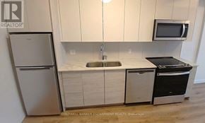 Kitchener condo for rent - A small kitchen with a refrigerator, microwave, sink, and oven.