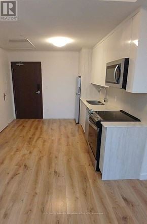 Kitchener condo for rent - A kitchen with wooden floors and white walls.