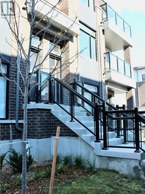 Pickering (Duffin Heights) townhouse for rent - A building with a black and white exterior and a tree in front.