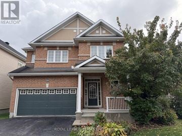 Ottawa apartment for rent - A house with a garage and a tree in front.