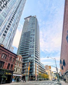 Toronto (Annex) condo for rent - A tall glass building stands in the middle of a city intersection.