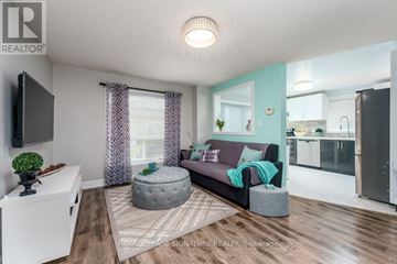 Barrie (Georgian Drive) apartment for rent - A living room with a grey ottoman and a grey couch with a green throw on it.