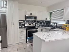Kitchener townhouse for rent - A kitchen with white cabinets and a black and white tiled backsplash.