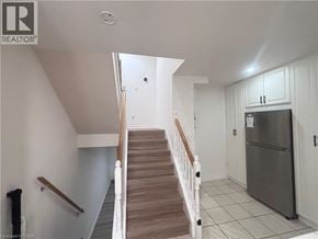 Kitchener townhouse for rent - A staircase in a house with a refrigerator in the kitchen.
