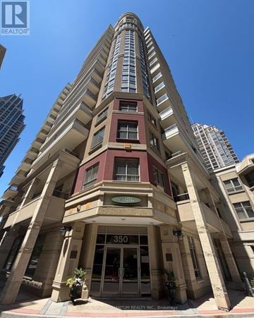 Mississauga (City Centre) condo for rent - A tall building with a red and beige facade stands in front of other buildings.