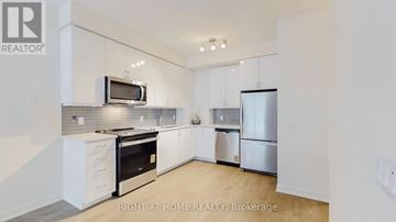 Toronto (Mimico) condo for rent - A modern kitchen with white cabinets and stainless steel appliances.