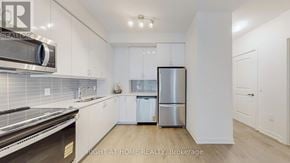 Toronto (Mimico) condo for rent - A modern kitchen with stainless steel appliances and white cabinetry.