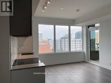 Toronto (South Parkdale) condo for rent - A modern kitchen with a large window overlooking the city.