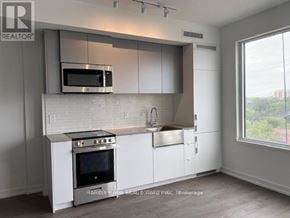 Toronto (South Parkdale) condo for rent - A modern kitchen with white cabinets and a stainless steel oven.