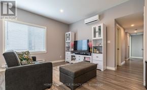 St. Catharines (E. Chester) apartment for rent - A living room with a grey couch, a brown ottoman, and a television on a cabinet.