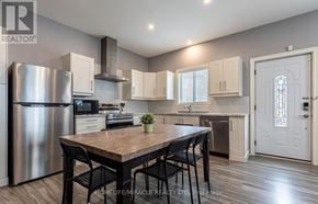 St. Catharines (E. Chester) apartment for rent - A kitchen with a table and chairs in the foreground and a refrigerator, microwave, oven, and sink in the background.