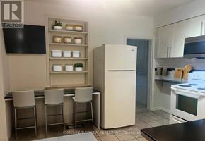 Toronto (Corso Italia-Davenport) apartment for rent - A kitchen with a refrigerator, a counter, and a TV mounted on the wall.
