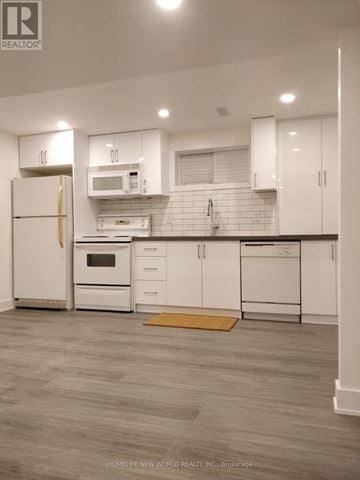 Toronto (Woodbine-Lumsden) apartment for rent - A kitchen with white cabinets and a microwave above the stove.