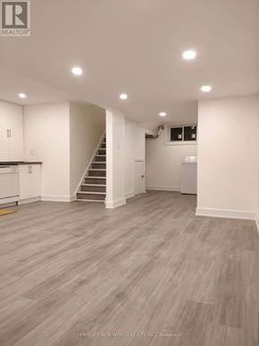 Toronto (Woodbine-Lumsden) apartment for rent - A spacious room with a staircase and a kitchen area.
