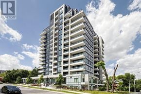 Toronto (Willowdale East) condo for rent - A modern multi-story building with a glass facade and a car parked in front.