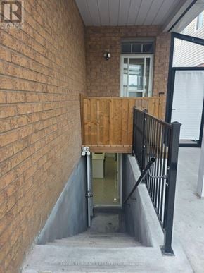 Oshawa (Pinecrest) apartment for rent - A brick wall with a wooden gate leading to a small door.