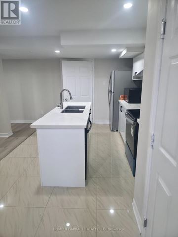 Oshawa (Pinecrest) apartment for rent - A white kitchen with a sink and a refrigerator.