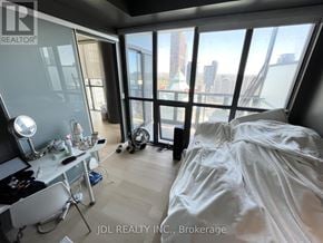 Toronto (Church-Yonge Corridor) condo for rent - A bedroom with a large bed and a desk with a chair.