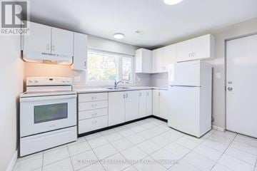 Brampton (Downtown Brampton) fourplex for rent - A white kitchen with a microwave, oven, and refrigerator.