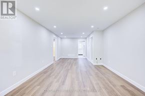 Brampton (Downtown Brampton) fourplex for rent - A spacious room with wooden flooring and white walls.