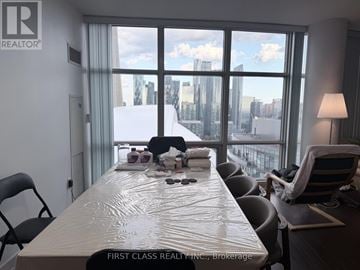 Toronto (Waterfront Communities) house for rent - A conference room with a long table and chairs, a lamp, and a view of the city through the windows.