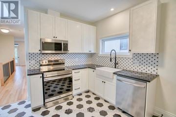 Ottawa duplex for rent - A kitchen with white cabinets and a black and white checkered floor.