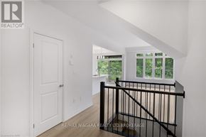 Niagara Falls (Cherrywood) townhouse for rent - A white interior with a black railing and a window overlooking a green outdoor area.