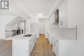 Niagara Falls (Cherrywood) townhouse for rent - A modern kitchen with white cabinets and a black railing.