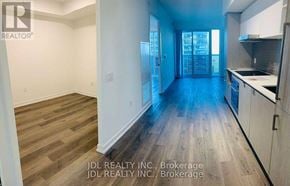 Toronto (Waterfront Communities) condo for rent - A spacious kitchen and living room with wood flooring and white walls.