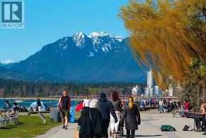 Vancouver apartment for rent - A group of people are walking on a path near a lake with a mountain in the background.