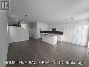 Ottawa apartment for rent - A spacious room with wooden flooring and white walls, with a kitchen area in the background.